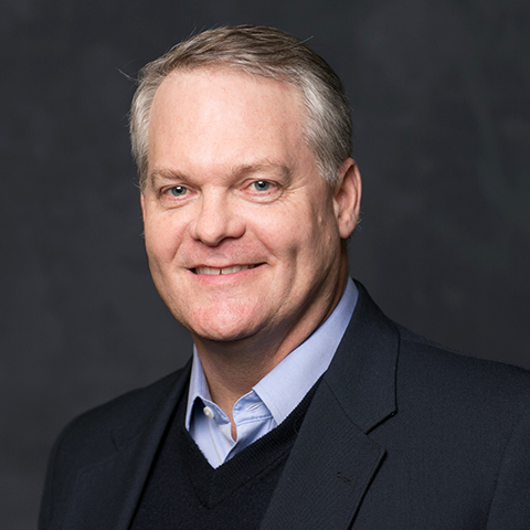 Man wearing a navy suit in front of a dark gray background