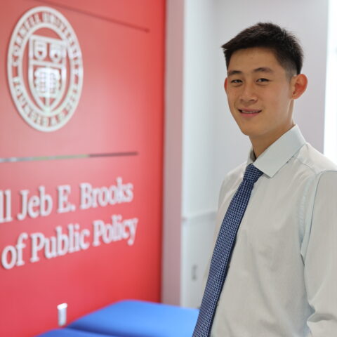 Andrew Juan '25 standing in front of the Brooks School seal.