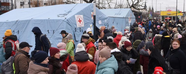 Group of refugees standing outside medic tents