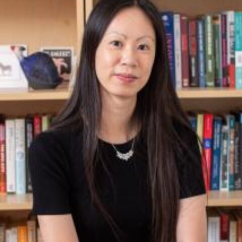 Woman smiling at camera with bookcase behind her