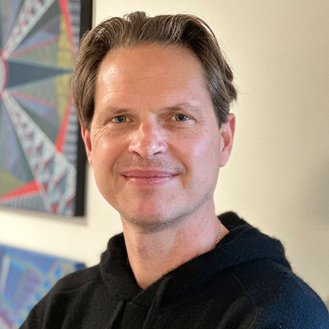 Giles Morris smiling with blue painting behind him