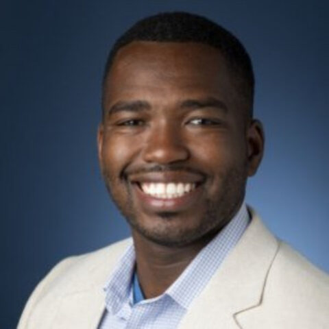 Man smiling at camera wearing a white blazer