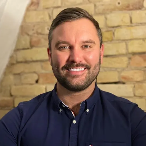 Man smiling at camera wearing a blue button up shirt