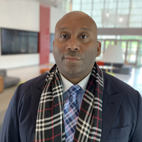 Bryan Sykes in plaid scarf and navy blazer