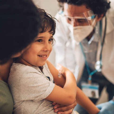 Child sitting in mother's lap getting a vaccination from a doctor