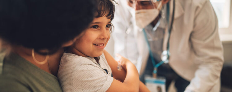 Child sitting in mother's lap getting a vaccination from a doctor