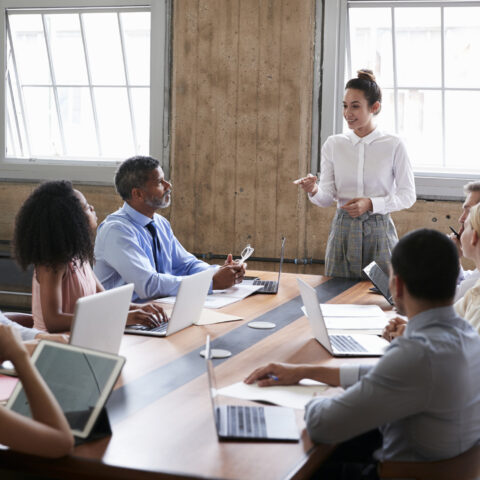 Female manager stands addressing team at a meeting